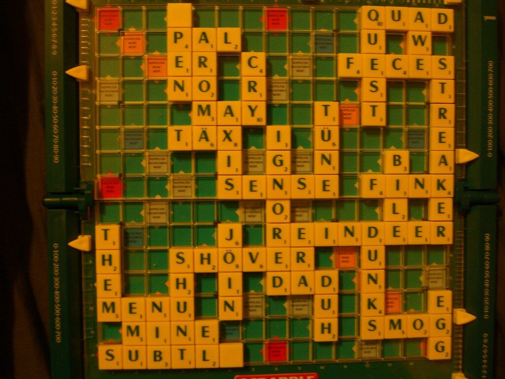 Deutsches Scrabble-Brett mit Buchstabensteinen, darunter Wörter mit Umlauten wie TÄXI und TÜN