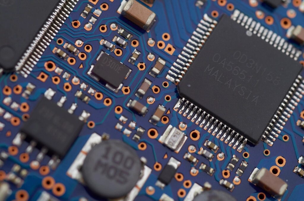 Nahaufnahme einer grünen Computerplatine mit Chips, Leiterbahnen und Bauteilen